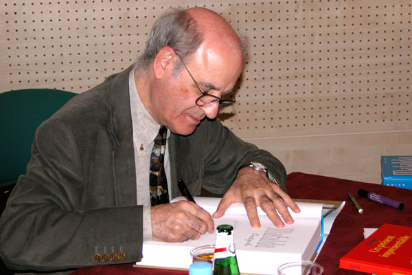 Fotografía de Quino autografiando un libro