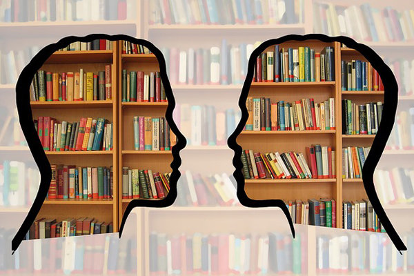 Imagen de una biblioteca con dos siluetas de cabezas delante.
