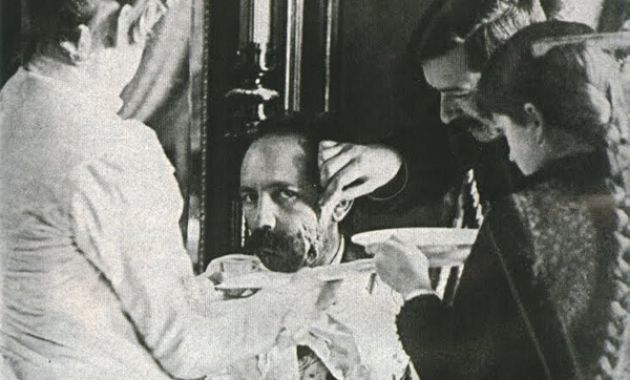 Fotografía de Máximo Santos mientras tres personas curan heridas en su rostro.