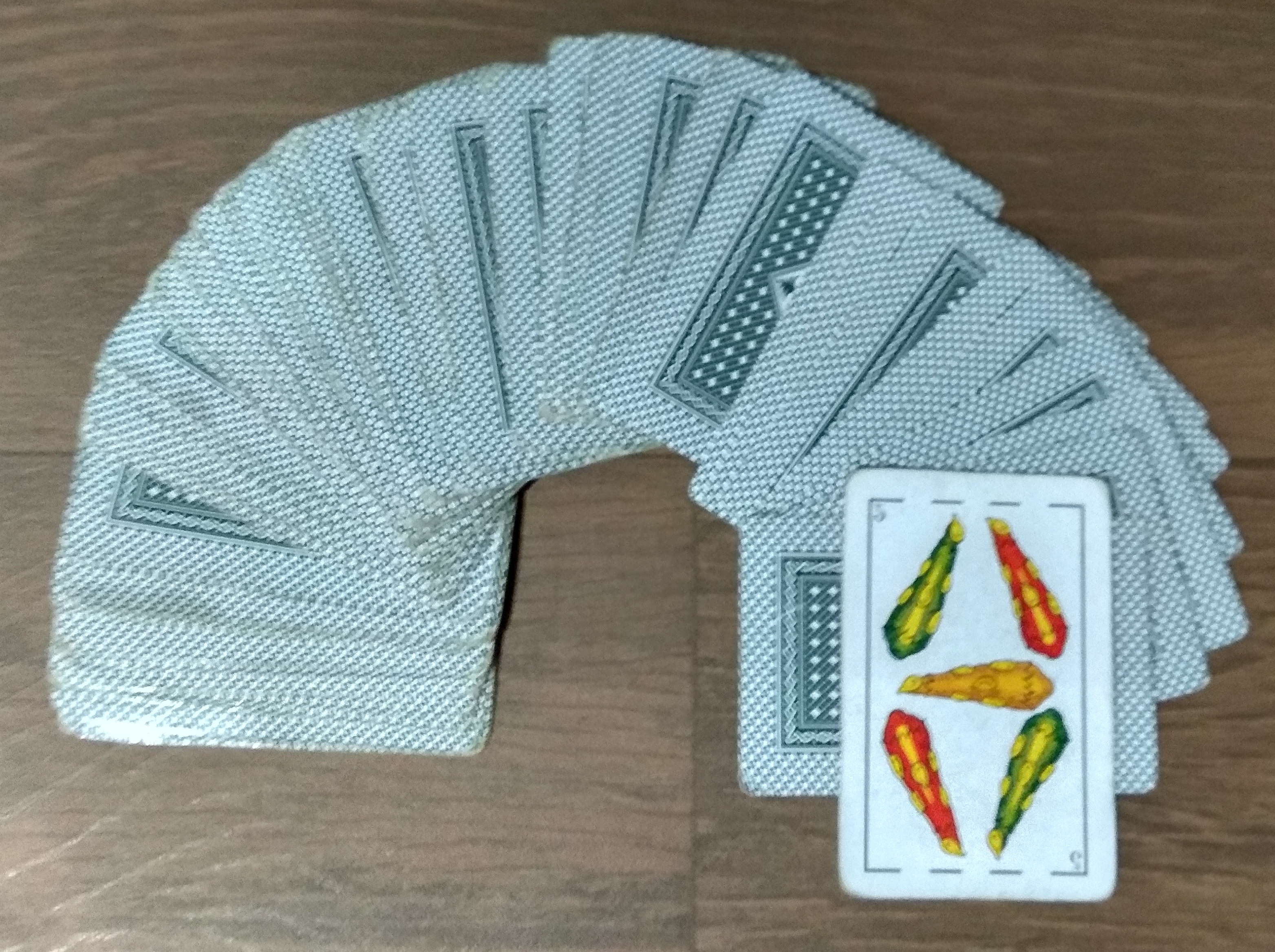 Mazo con cartas de las cuales se ve una que corresponde a u 5 de basto