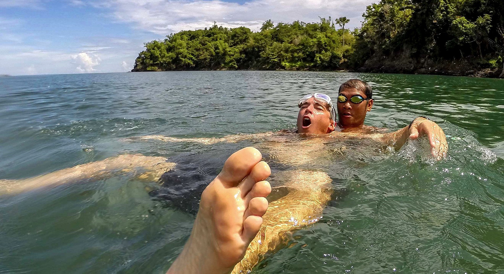 Dos personas en el agua una de ellas nada cargando con la otra que flota boca arriba