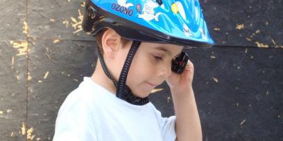 Niño con casco protector mientras habla por celular.