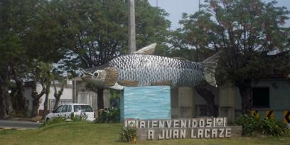 Monumento de un sábalo ubicado en una plaza sobre un cartel que dice "ienvenido a Juan Lacaze"