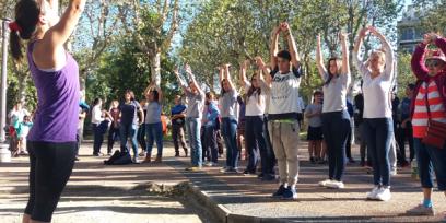 Fotografía de una profesora dirigiendo clase de gimnasia aeróbica en una plaza.