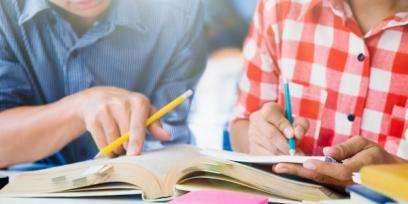 Imagen de dos estudiantes repasando juntos un libro.