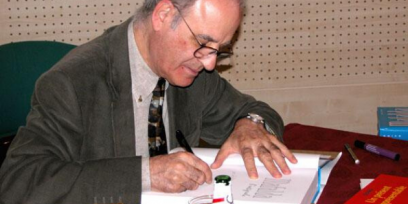 Fotografía de Quino autografiando un libro
