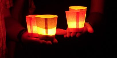 Velas encendidas dentro de vasos de papel sobre las manos. Imagen libre de derechos de autor. 