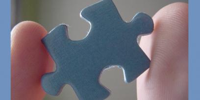 Imagen de un par de dedos sosteniendo una pieza de puzzle de cartón