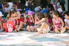 Fotografía de niños riendos, sentados en el piso.