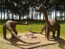 Fotografía de la representación de dos dinosaurios de cuello largo rodeando un nido. 