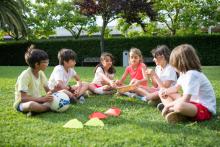 grupo de niños sentados de forma circular sobre el césped