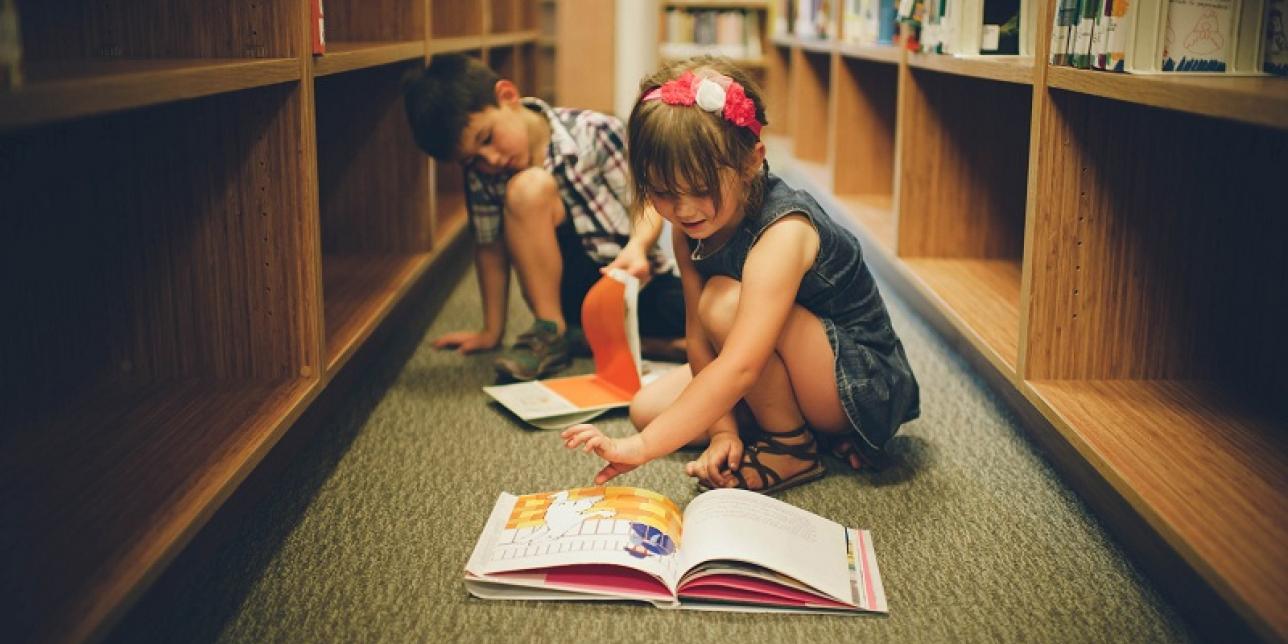 Niños leyendo libros cerca de biblioteca