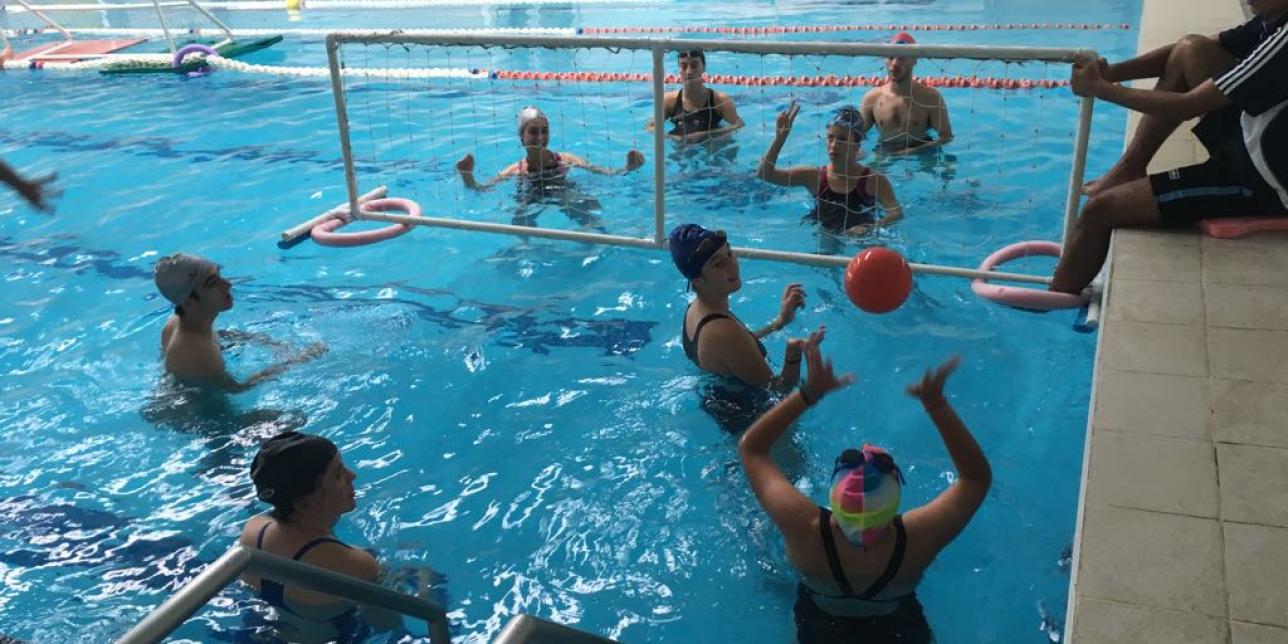 Jóvenes jugando a juego con pelota y red en la piscina.