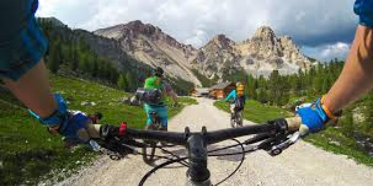 Ciclista subiendo cordillera con paisaje de montañas.