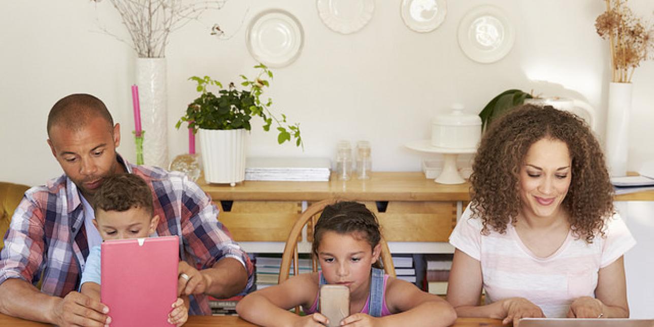 Familia utilizando diversos dispositivos como celular, tablet y notebook