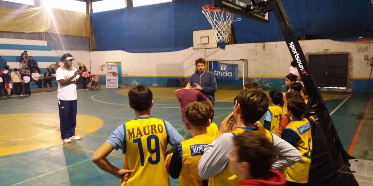 Profesor explicandole a alumnos sobre lanzamiento en Básquetbol.