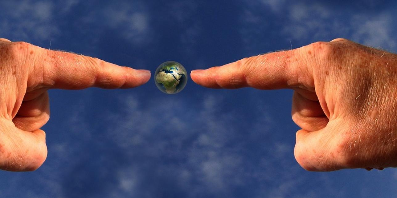 Imagen que muestra dos manos señalando el planeta Tierra