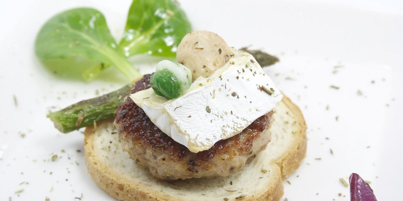 Imagen que muestra una preparación comestible y decorada, que incluye verduras, pan, queso