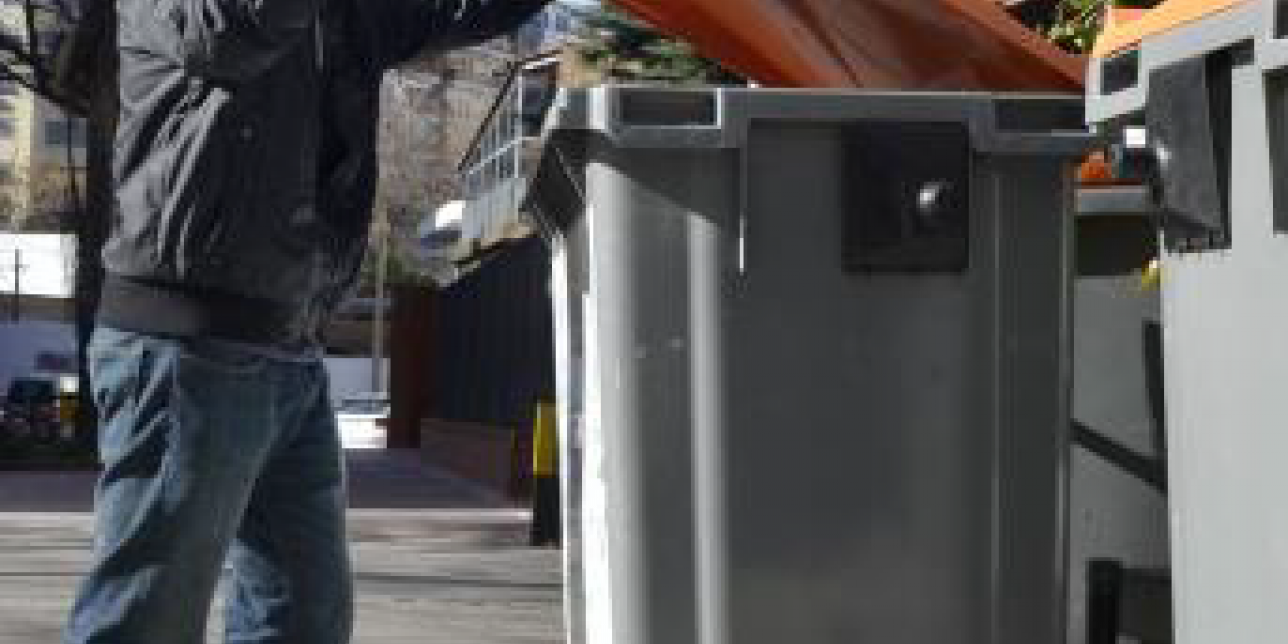 Persona tirando basura en un contenedor.