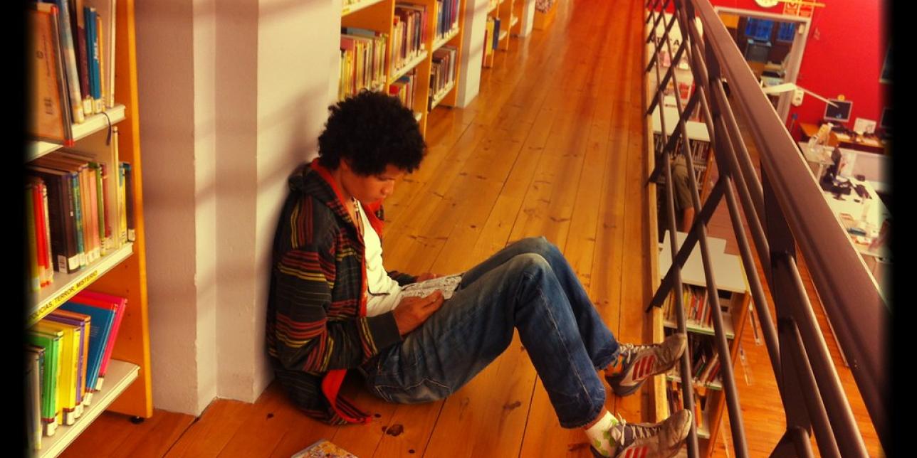 Joven leyendo un libro en una biblioteca.