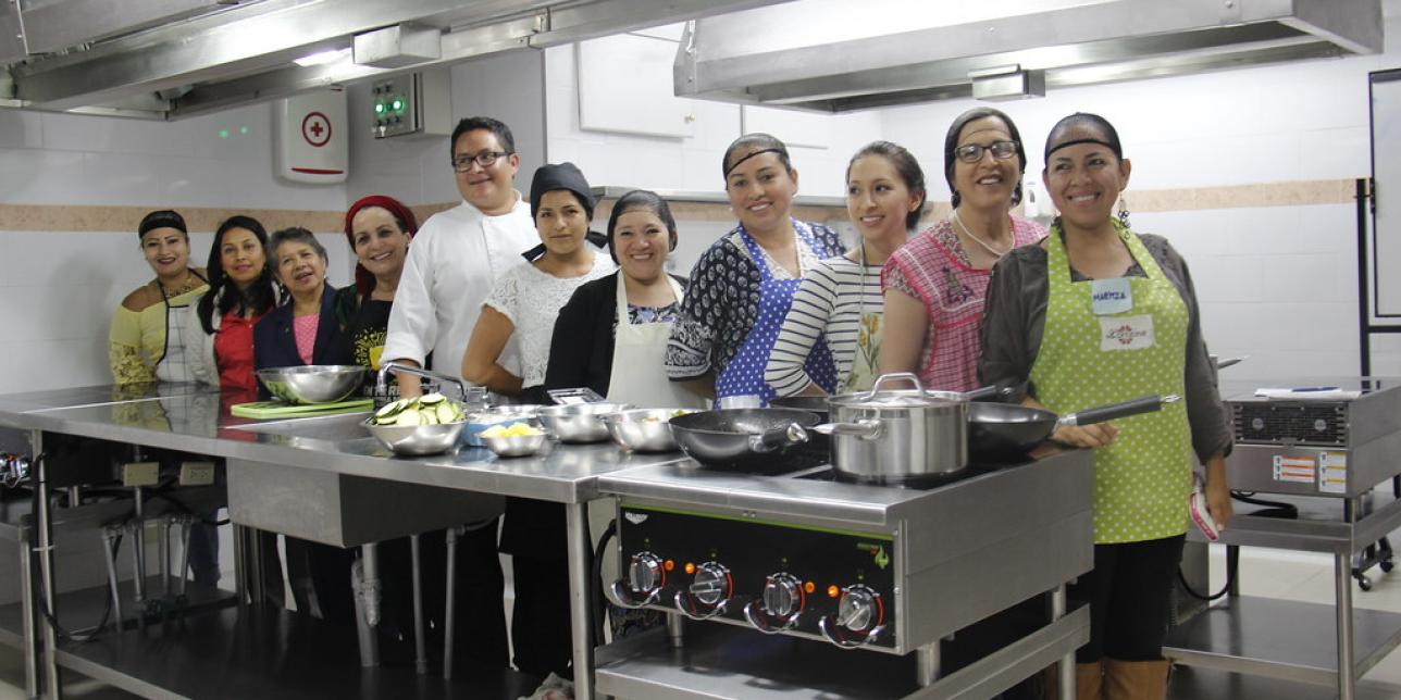 Jovenes atras de una mesada,  en un taller de cocina.