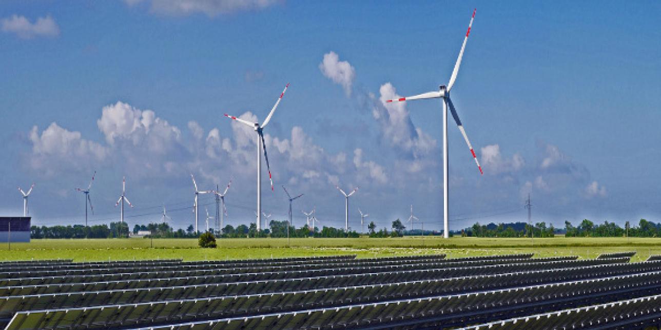 Foto campo con paneles solares y molinos eólicos.