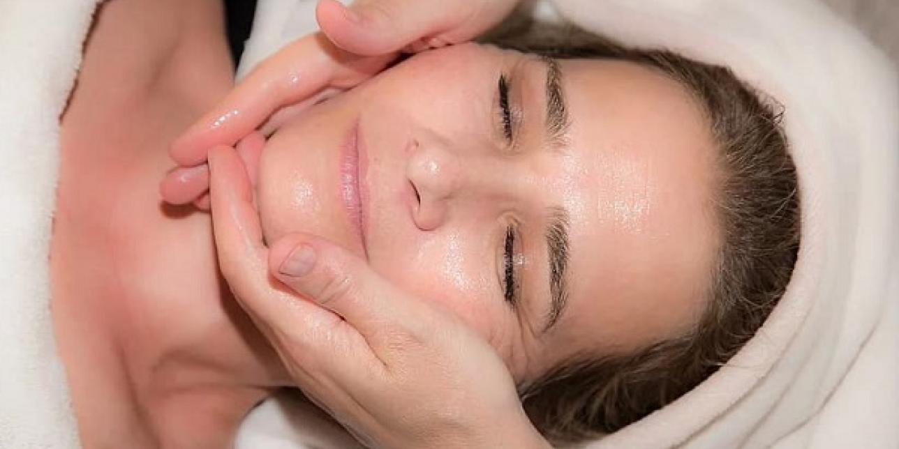 Fotografía de rostro al que le aplican una crema facial