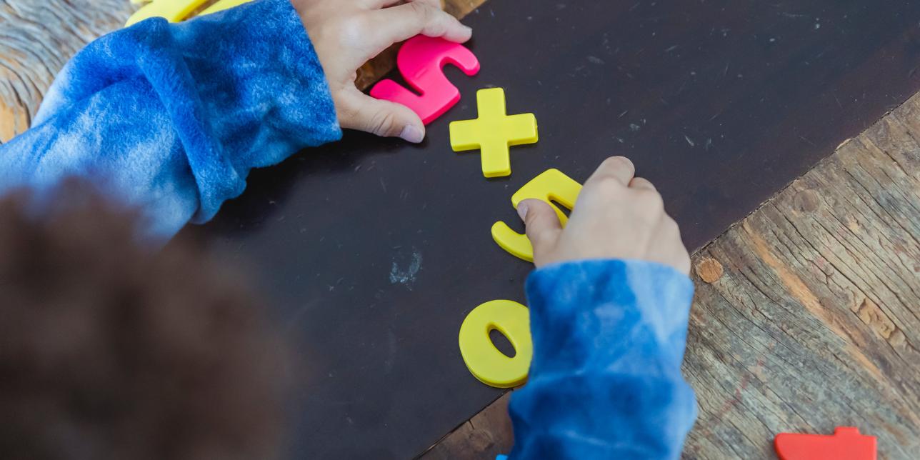 Niño planteando con números de juguete la multiplicación 5x5