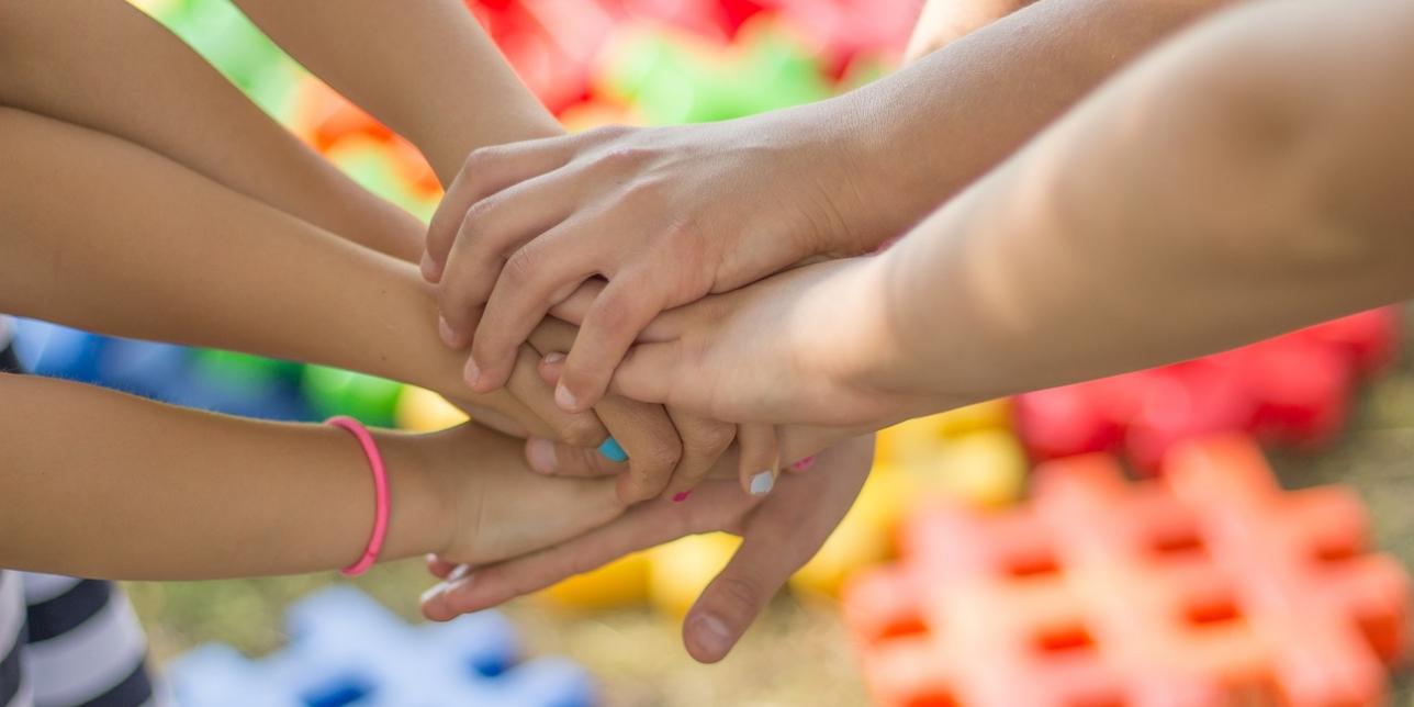 Manos unidas al centro con varios niños en ronda