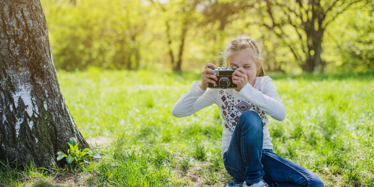 niña tomando fotografía en un parque