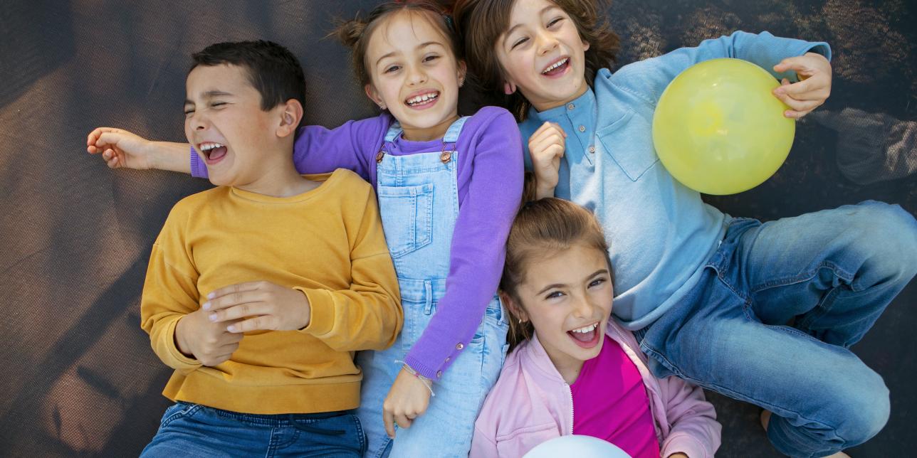 Niños riendo juntos, acostdos en el suelo.